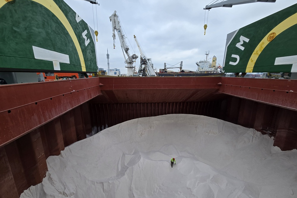 Eine Schiffscontainer voll Salz, in dessen Mitte eine Person steht, die im Größenverhältnis als kleiner Punkt erscheint