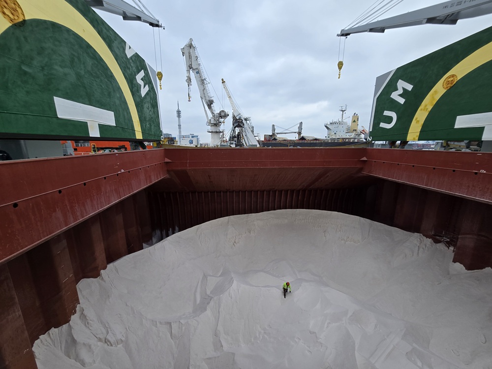 Eine Schiffscontainer voll Salz, in dessen Mitte eine Person steht, die im Größenverhältnis als kleiner Punkt erscheint